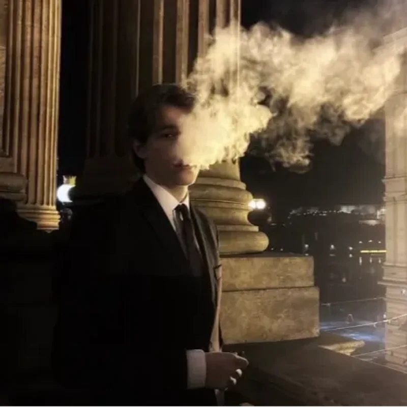 Orka in a dark suit between stone columns at night